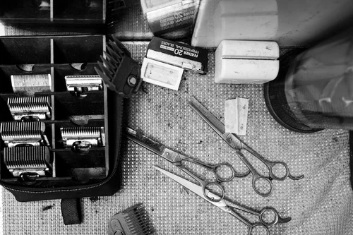 Clippers, scissors, and a comb laid out on the work counter.
