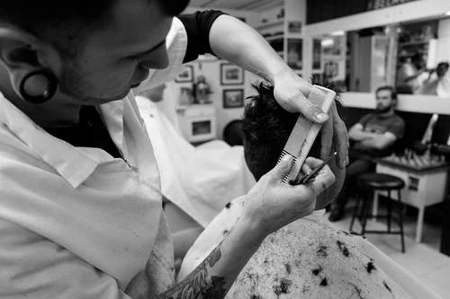 A barber at Andre's combs and trims a customer's hair.