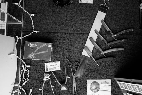 Straight razors and scissors arranged on a workbench.