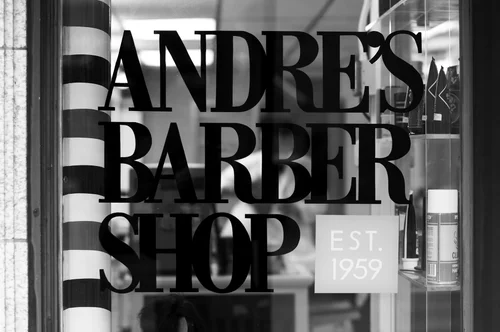 The Andre's Barber Shop storefront window, painted in classic black serif lettering.